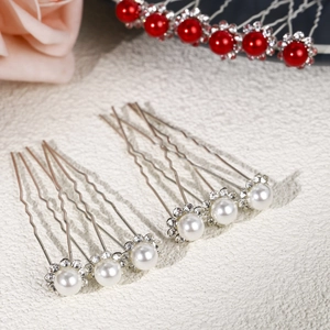 Détails macro d'épingles à cheveux en perles et strass sur une surface en pierre blanche