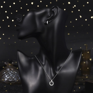 Detailed close-up of luxury silver-tone necklace and earrings set on a black mannequin