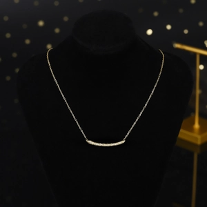 Goldene Titan-Halskette mit gebogenem Kristallanhänger auf schwarzem Samt-Display
