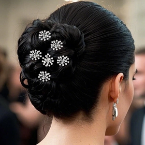 Detailed view of six snowflake-shaped pearl hair pins elegantly styled in a dark hair bun