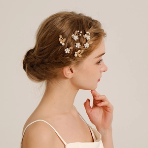 Detailed macro view of white flower hair pins with pearls and golden leaves on model hair