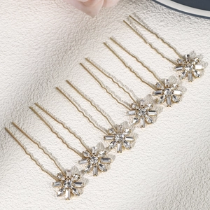 Detailed view of seven gold U-shaped bridal hair pins with snowflake rhinestone motifs