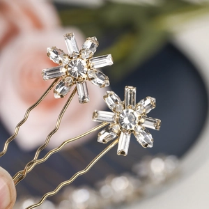 Close-up of golden U-shaped hairpins with sparkling snowflake rhinestone accents for bridal hair