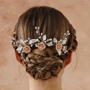 Detail of pink floral bridal hairpiece with pearls and crystals in a braided hairstyle
