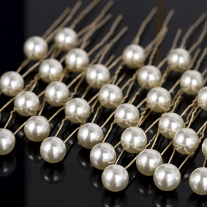 Vue macro d'élégantes perles blanches sur des épingles à cheveux dorées en U avec reflet
