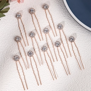 Close-up of 12 rose gold U-shaped hair pins with sparkling rhinestones for bridal hair