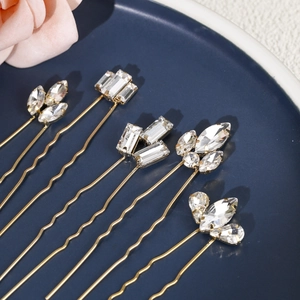 Close-up of five gold bridal hair pins with clear rhinestones in various floral designs