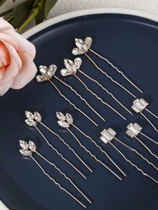 Detail view of nine rose gold U-shaped bridal hair pins with leaf and geometric rhinestones
