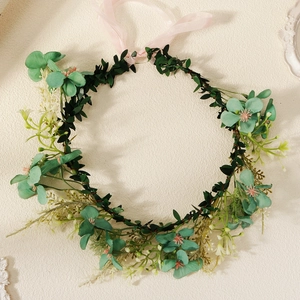 Detailed macro view of handmade flower crown with green leaves and pink ribbons
