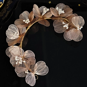 Macro detail of delicate gold wire woven floral petals with center pearls for bridal hair