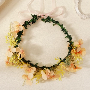 Close-up of floral crown with pink faux flowers and silk ribbon for wedding decoration