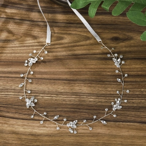 Elegant silver bridal headpiece with crystals and white ribbons on a rustic wood surface