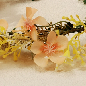 Close-up detail of realistic orange-pink fabric flowers and yellow buds on wreath