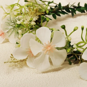 Detailed close-up of handmade white floral headband with realistic petals and green leaves
