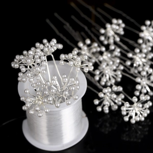 Detail view of U-shaped hair pins with white pearls and silver wire on a black base