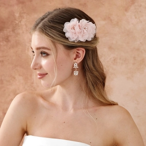 Détail d'un peigne à cheveux fleur en tulle rose avec perles et boucles d'oreilles cristal