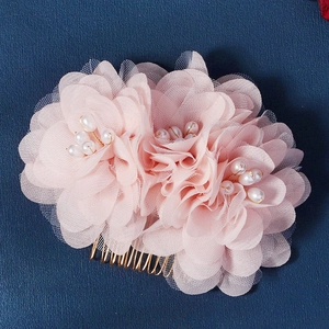 Peigne à cheveux fleur rose avec perles et dents dorées sur fond bleu texturé