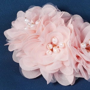 Gros plan sur une fleur en tulle rose avec perles blanches sur fond cuir bleu