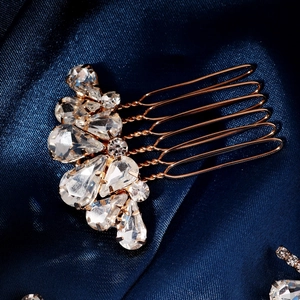 Nahaufnahme des goldenen Brauthaarkamms mit glänzenden Strasssteinen auf dunkelblauer Seide