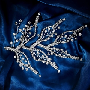 Macro shot of silver bridal hairpiece with shimmering crystals on dark blue silk