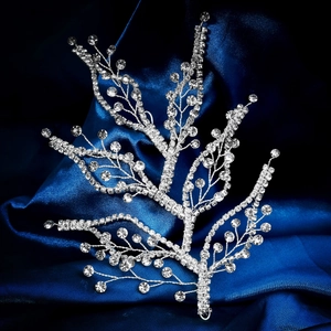 Detailed view of silver bridal hairpiece with shimmering crystals on dark blue silk fabric