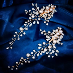 Gros plan de branches dorées avec perles blanches et feuilles sur satin bleu foncé