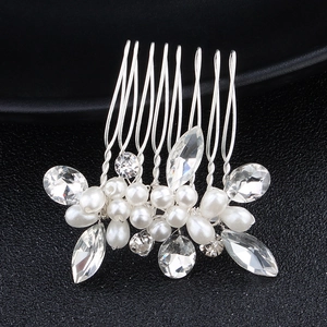 Detailed macro view of silver floral hair comb with sparkling rhinestones and white pearls