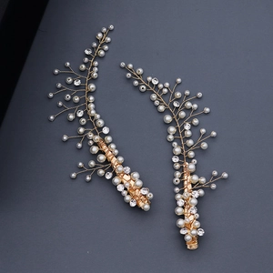 Détail de barrettes dorées faites main avec perles et cristaux sur fond gris neutre