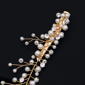 Détail d'une pince à cheveux dorée faite main avec perles blanches et strass
