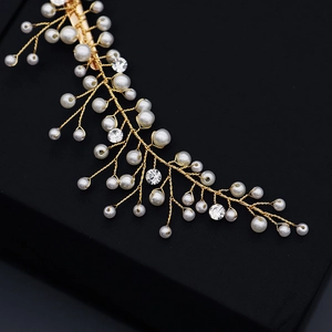 Détail d'une épingle à cheveux dorée faite main avec perles blanches et strass étincelants