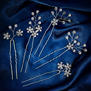 Detailed view of silver bridal hair pins with clear rhinestones on blue satin fabric