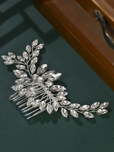 Detail of silver bridal hair comb with sparkling rhinestones on green background