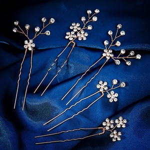 Close-up of 5-piece rose gold rhinestone plum flower bridal hair pins on blue silk