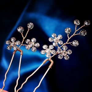 Detail of two handmade gold-plated bridal hair pins with clear rhinestone floral patterns