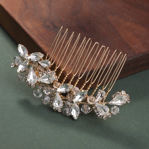Close-up of golden bridal hair comb with shimmering crystals and elegant leaf details