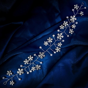 Detail view of handmade silver bridal hair vine with rhinestone flowers and white pearls