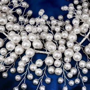 Détail macro de perles blanches tissées avec du fil argenté sur fond satiné bleu