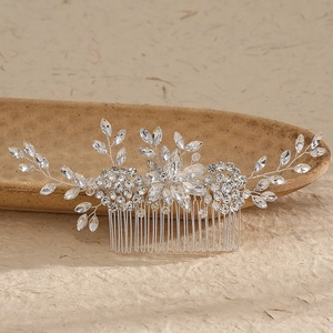 Close-up of a silver bridal hair comb with sparkling rhinestones on a ceramic dish