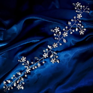 Detail of silver bridal hair vine with sparkling rhinestones and white pearls on blue silk