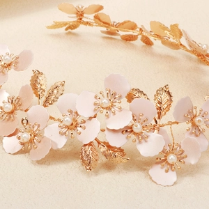 Dettaglio dei petali di fiori rosa e foglie dorate su un cerchietto fatto a mano