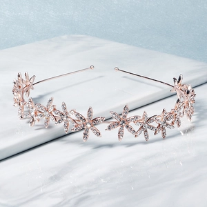 Dettaglio di tiara floreale in oro rosa con strass scintillanti su sfondo di marmo