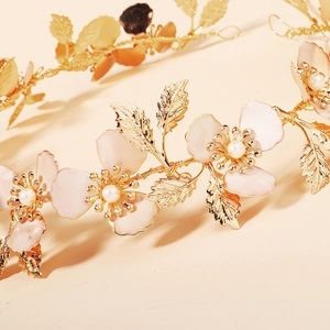 Dettaglio della fascia dorata intrecciata con fiori rosa, perle e foglie in metallo