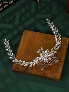 Detail of silver bridal hair comb with marquise crystals on a rustic wooden stand