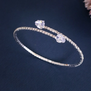 Detail of silver open bangle featuring dual pear-shaped crystals and shimmering pavé setting
