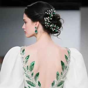 Detail view of emerald green crystal hairpiece and matching drop earrings on bride
