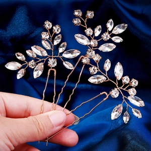 Macro view of rose gold bridal hair pins with marquise crystals on blue silk