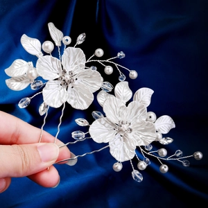 Détail d'épingles à cheveux fleurs en satin blanc avec perles et cristaux sur soie bleue