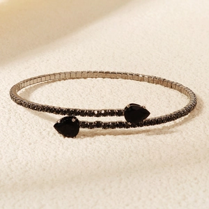 Detailed macro shot of silver bangle featuring two pear-cut black gemstones with claw settings