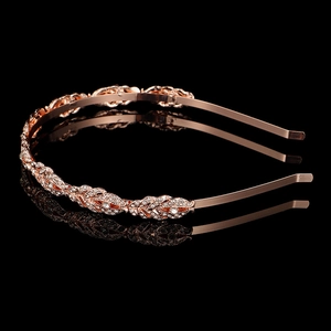 Dettaglio della tiara a foglia oro rosa con strass scintillanti su fondo nero riflettente