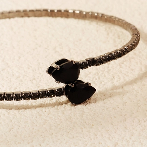 Macro shot of sparkling black pear-shaped gemstones on a minimalist silver-toned bangle